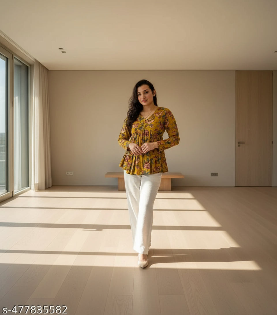 Woman wearing a yellow floral blouse standing in front of a glass block wall.
